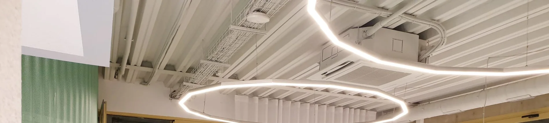 Detalle del techo de LOAL: un tubo de LED continuo recorre la nave y forma un aro suspendido sobre la recepción.